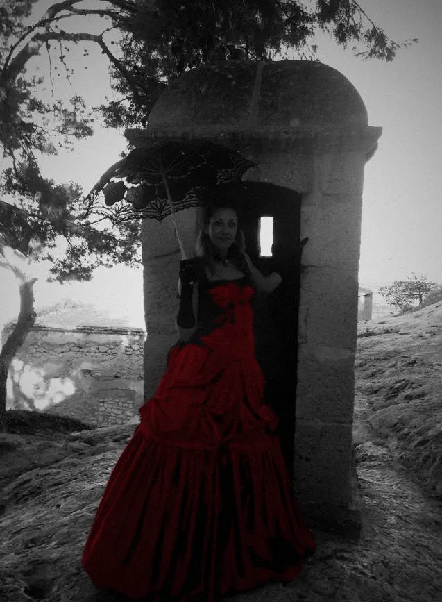 Mari Carmen Pacheco Picazo con vestido rojo junto a una garita de piedra
